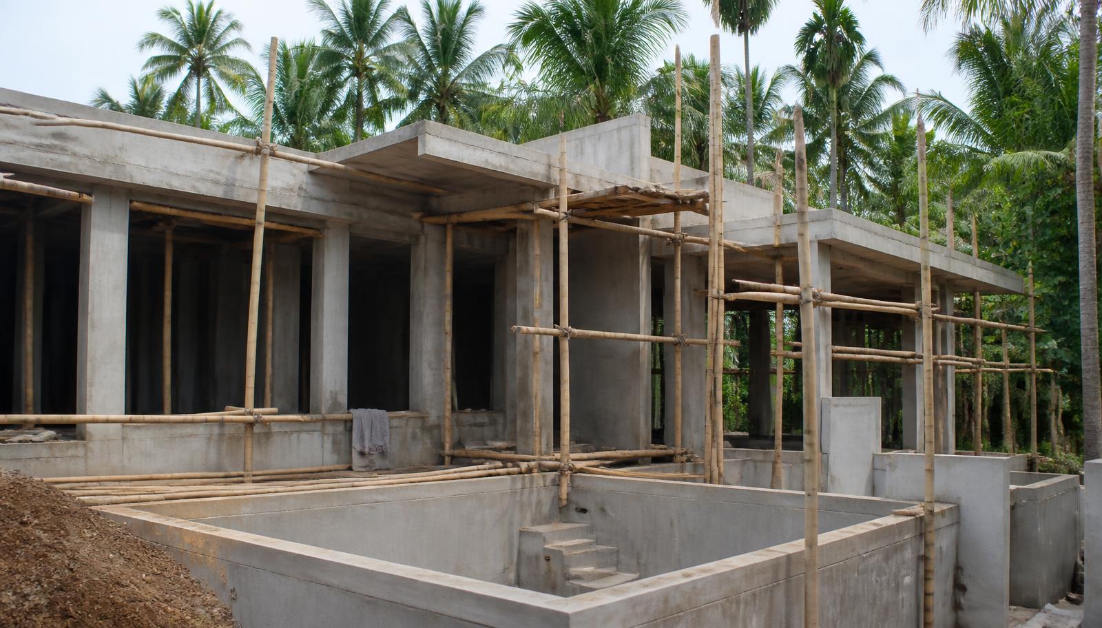 Villa in aanbouw op Bali met betonstructuur en bamboe steigers tussen palmbomen