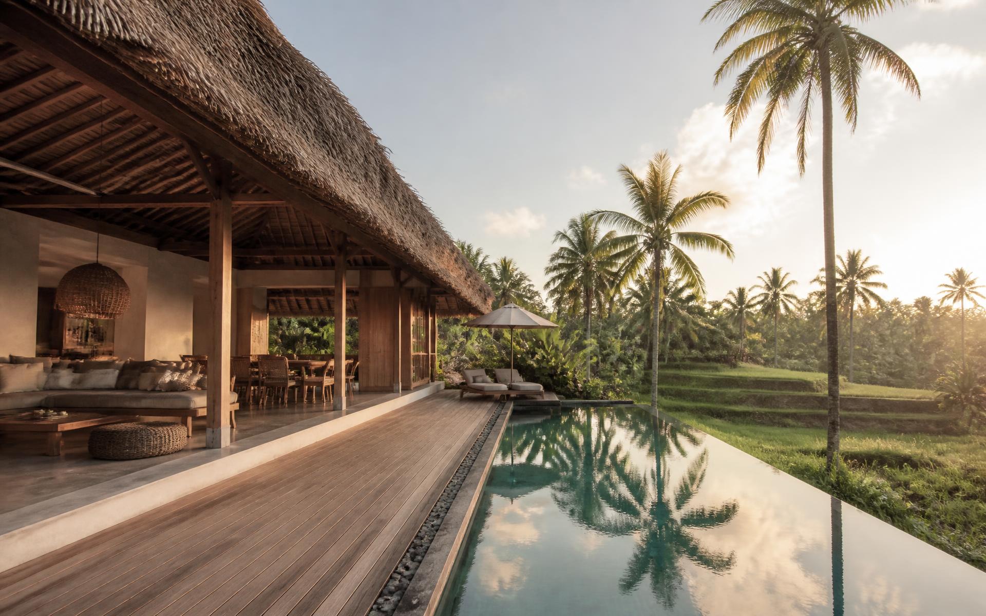 Balinese villa met open woonpaviljoen, houten terras en lange pool aan de rand van rijstvelden